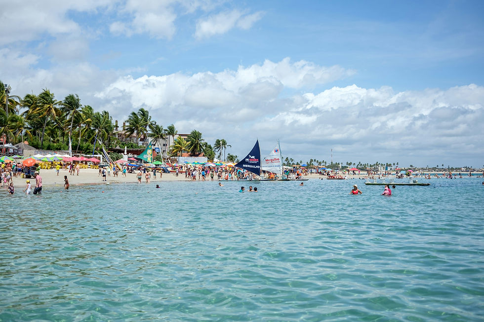 People swim in the crystal clear water at Porto de Galinhas, in front of some small boats