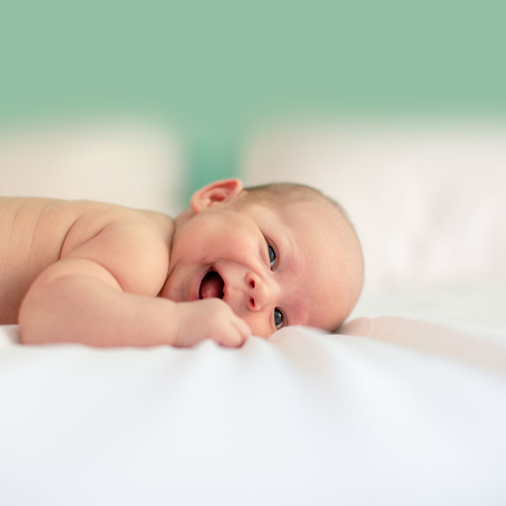 Newborn Photography by Blake Ferguson depicts a Laughing Baby on a Bed in Ontario, Canada.