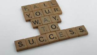 Scrabble tiles spelling out the sentence, "Fail your way to success"