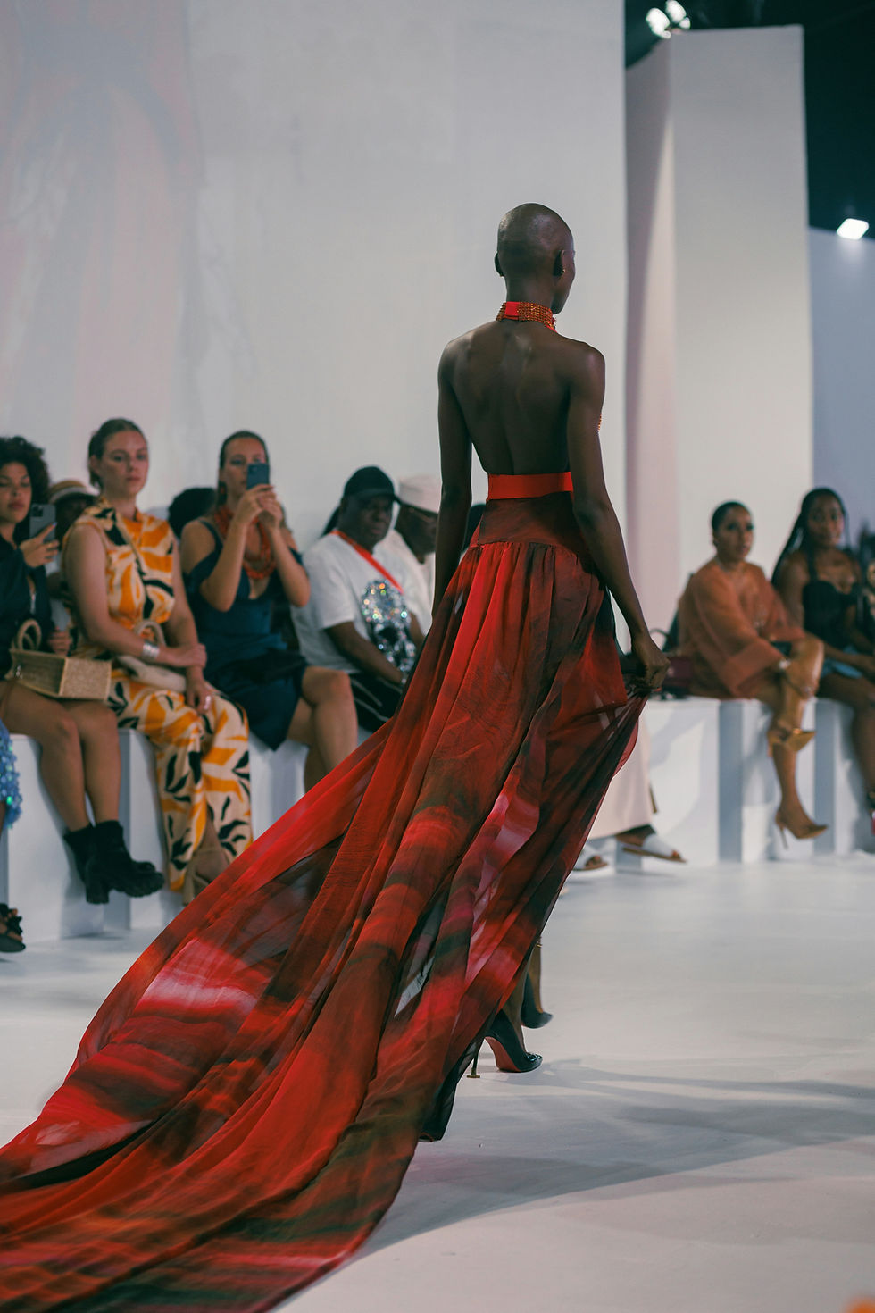 black model with long red dress walking on the runway