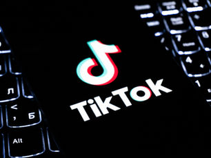 ikTok logo on a black phone screen over a backlit keyboard, with the Alt key visible in the foreground.