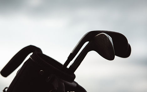 Man wearing Onyx Black Performance Golf Polo on green.