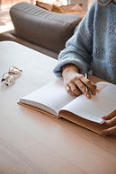 woman's hand holding pen, open journal, glasses