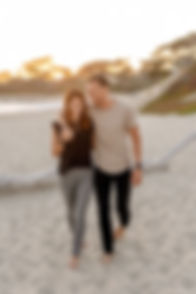 Image of man and woman holding hands. Man has his arm around the woman as they walk on the beach. image by Allen Taylor