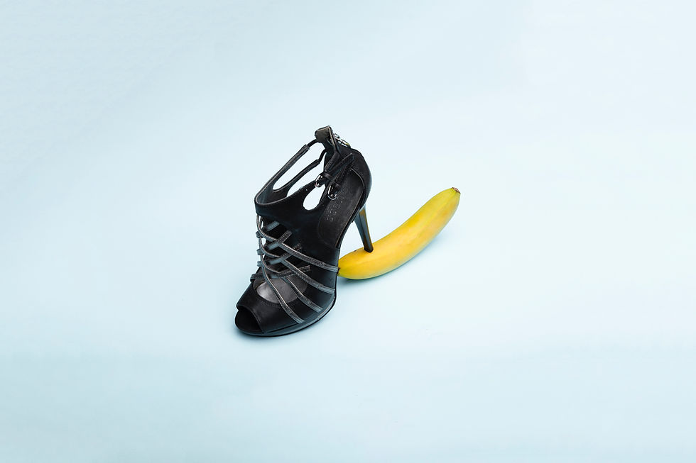 Strappy black high heel stepping on end of banana