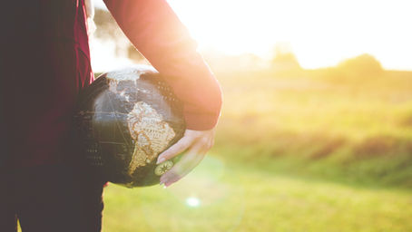 Person holding a world globe outside representing the global importance of learning Spanish today
