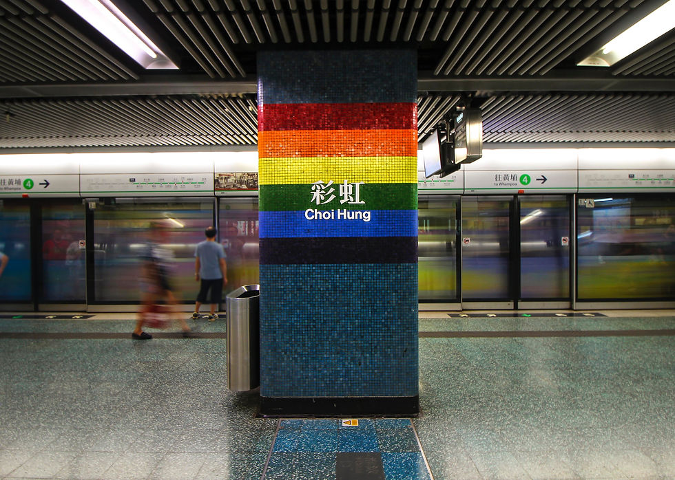 Choi Hung MTR station with rainbow sign on the pillar and MTR train arriving at station.