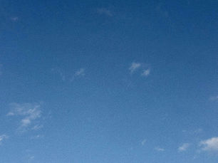 Clear blue summer sky with a few light, scattered wispy clouds.