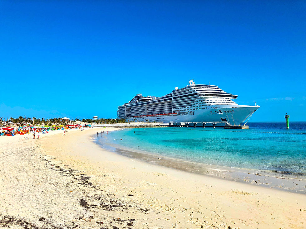 A large cruise ship docked by a sandy beach with colorful umbrellas and people relaxing. Clear blue sky and turquoise sea create a serene mood.