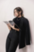 Brown haired woman holding vogue magazine reading in black attire