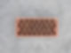 Orange perforated brick laid flat on a gray concrete surface, showing rows of circular holes