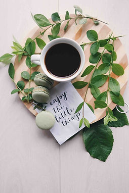 A coffee cup on a table with plants and motivational words.