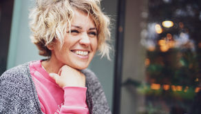 A woman in her 40s with a natural smile photographed in soft warm light, representing perimenopause oral health and the impact of hormonal changes on teeth and gums from Vibrance Way.