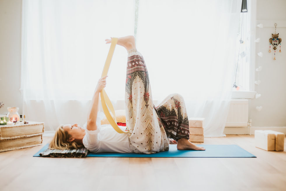 Middle-aged woman lying on her back, using a stretching strap to pull her leg toward her torso, performing a hamstring stretch for improved flexibility and mobility.
