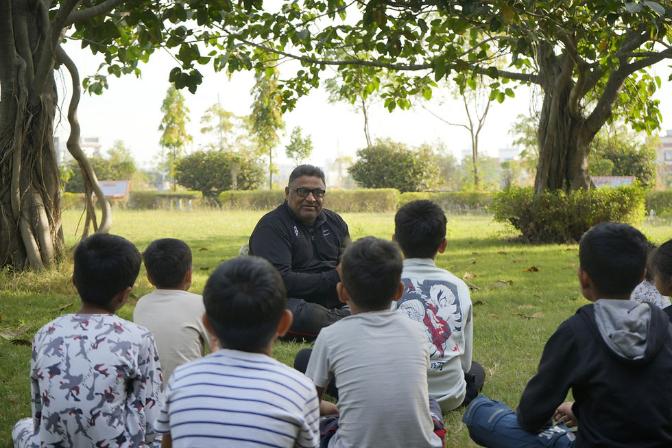 Man seated outside facing group of seated younger students in outdoor setting