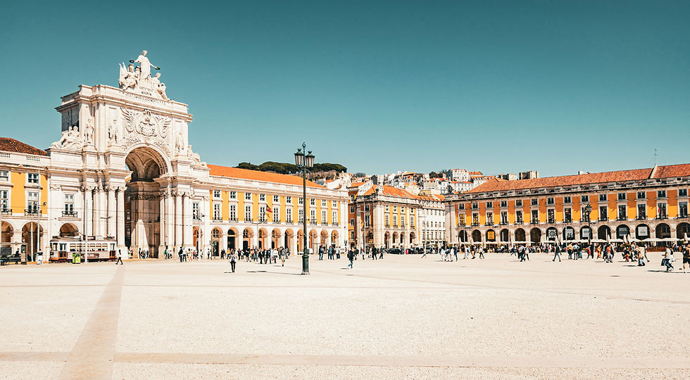 Sunny Lisbon plaza Praça Do Comércio with ornate white arch, yellow arcades, and crowds walking under a clear blue sky. This is where the Lisbon Marathon finishes.