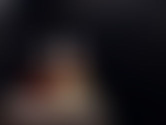 مجموعة من منتجات العناية تتضمن شمعة عطرية، صابونة طبيعية، وعبوتين خشبيتين بمضخة، موضوعة على طاولة حمام بلون رمادي داكن بأجواء دافئة ومريحة