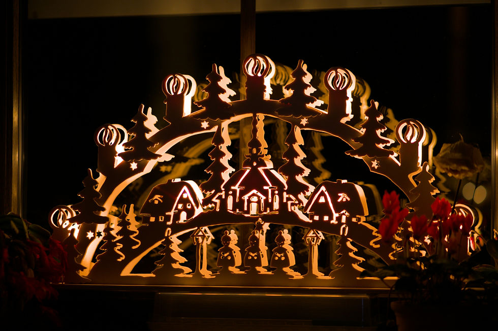Close-up view of carved Erzgebirge wooden figures and a glowing Schwibbogen at a Christmas stall.
