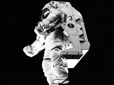 Astronaut in white suit with NASA logo floats in space, wearing a helmet. Dark background. Calm and isolated scene.