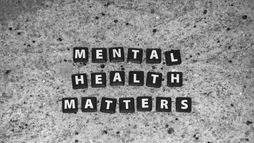 Black letter tiles spelling “Mental Health Matters” on a speckled granite surface, in a monochrome style, symbolizing mental health awareness and the importance of clinical mental health counseling.
