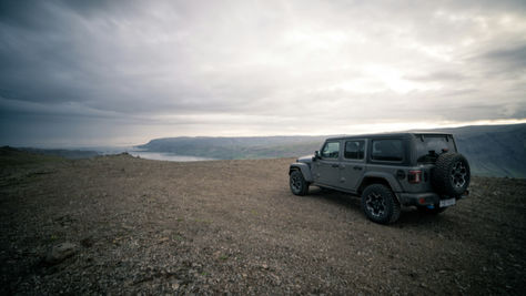 4x4 vehicle on a remote gravel plateau in Iceland’s Westfjords overlooking rugged fjords and coastline under dramatic skies.