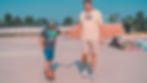 adult teaching kid child learning how to skateboard at skatepark Image by Anderson Schmig