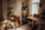Cozy room with a map on the wall, skateboard, books, and plants. Sunlit wooden desk filled with books and a 3D printer. Relaxed atmosphere.