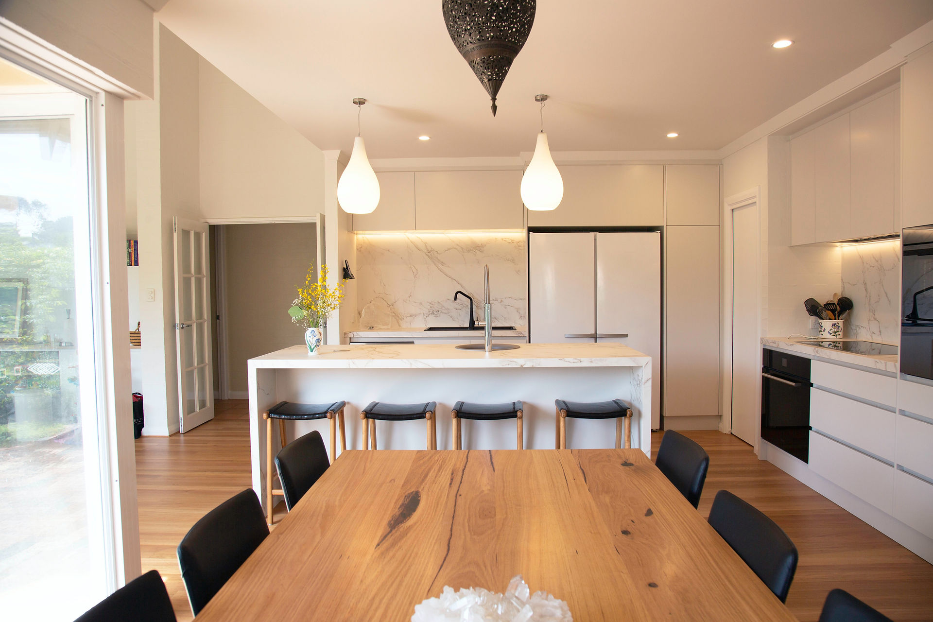 Task lighting and overhead lighting in a white kitchen with island.