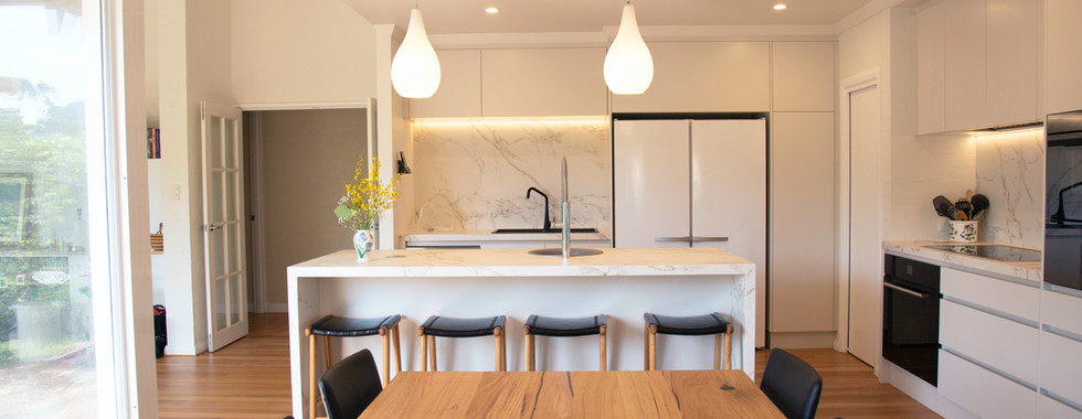 Task lighting and overhead lighting in a white kitchen with island.