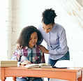 Mother with hands on her teen daughter’s shoulders, helping her with homework at home