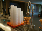 Four stacks of reusable cups on a coffee bar, surrounded by coffee equipment.