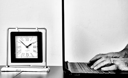 A man typing on a laptop next to an analogue desktop