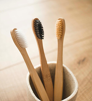 Three wooden toothbrushes are in a toothbrush holder