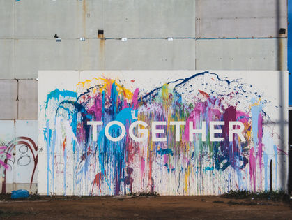 A vibrant public art installation features a splash of rainbow colors with the word "Together" boldly displayed, symbolizing unity and collaboration.