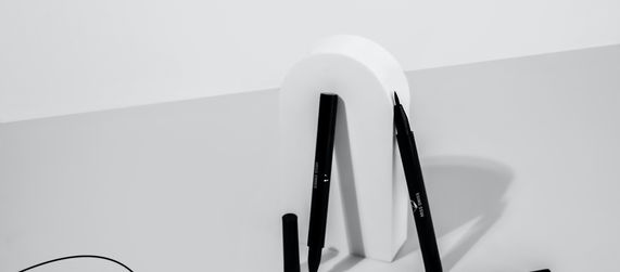 Three black eyeliner pens, one drawing a wavy line