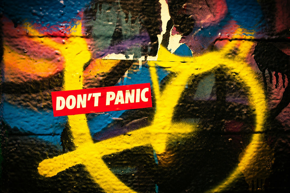 black wall with graffiti and a sticker that says "don't panic"