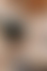 Person using a laptop with editing software on screen, holding a cup of coffee in a cozy setting. Wearing a watch; warm, focused vibe.