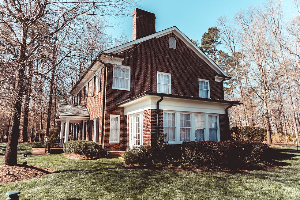 Large red brick house with white trim, set in a grassy yard with bare trees. Clear blue sky, evoking a tranquil, crisp atmosphere.