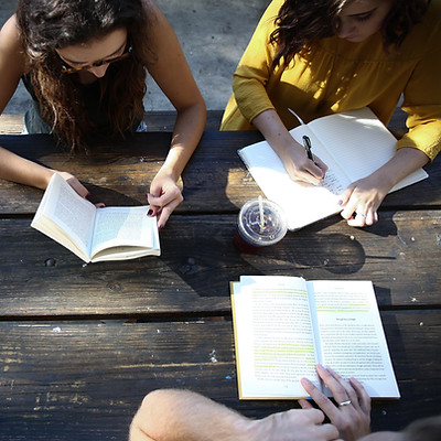 Image of people reading and journaling at a table by Alexis Brown