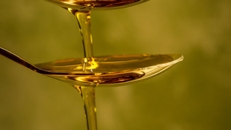 Olive oil being poured into spoons, demonstrating the benefit of vegetable oils for heart health