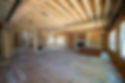 New house construction interior with exposed wooden framing, ceiling joists, and windows.