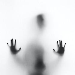 Blurred silhouette behind frosted glass, illustrating exhaustion and burnout