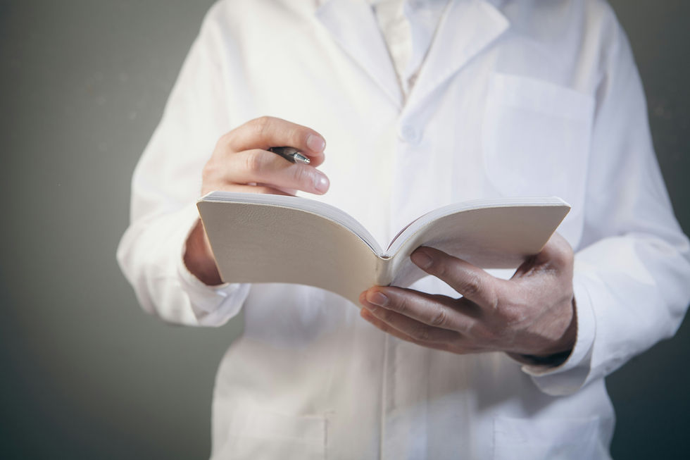 A doctor is writing on notes holding pen in hand.
