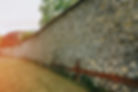 Long stone wall featuring pebble dashing with irregular stone texture.