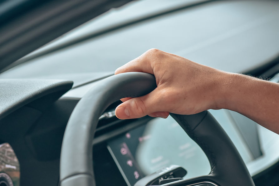 close-up image of a person's hand on steering wheel