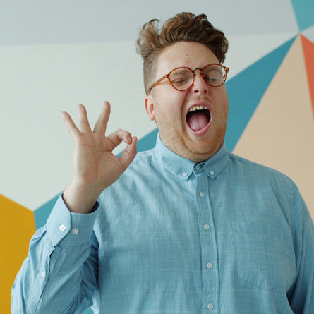 Man winking and making an “OK” hand gesture, representing people-pleasing and the pressure to reassure others that everything is okay.