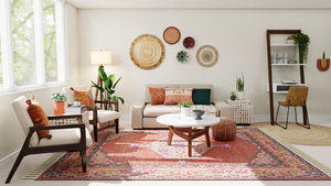 Stylish living room with beige sofa, colorful cushions, wooden chairs, and a vibrant patterned rug. Sunlit, with wall decor and plants.