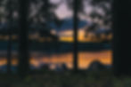 Image of a camsite right next to a lake and the sun is setting.