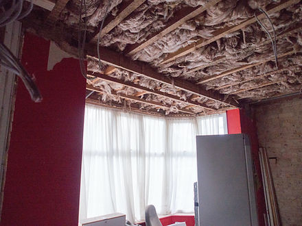 Water-damaged ceiling torn open with insulation exposed