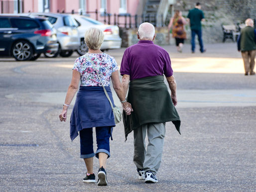 A thoughtful, mature business owner standing by a large window in a modern office, looking out over the city, reflecting on succession, retirement, and life after leading a company.